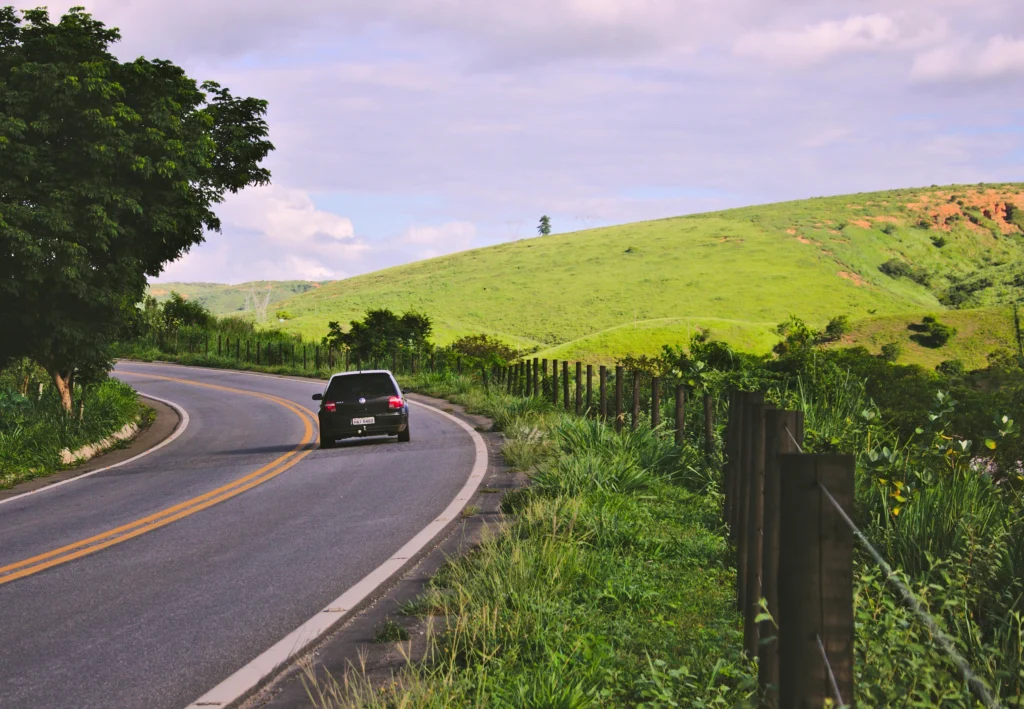 Car on the road through green hills