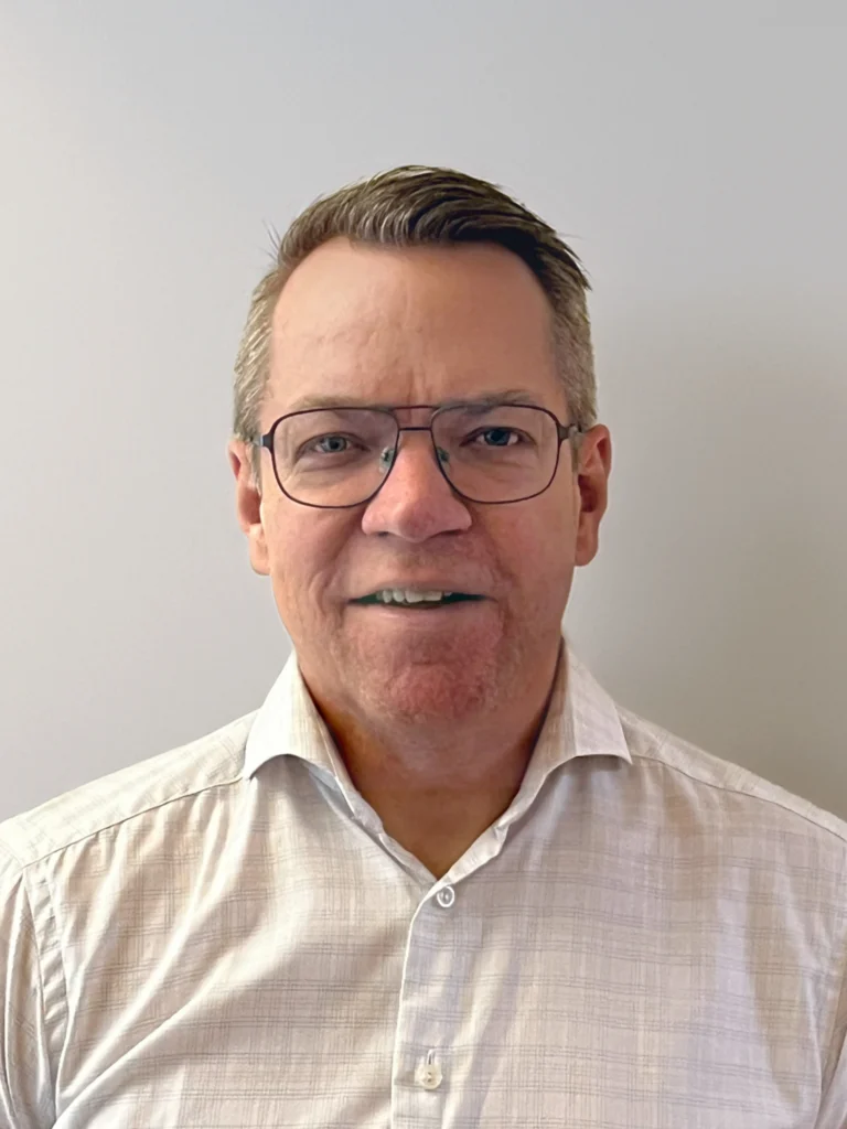 Man med glasögon och vit skjorta.